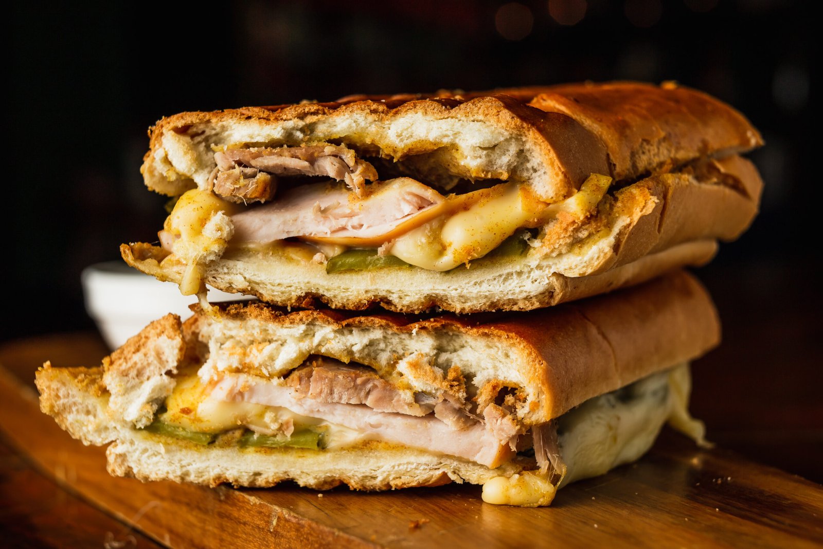 Traditional cuban sandwich with cheese, ham and fried pork, served on a wooden board